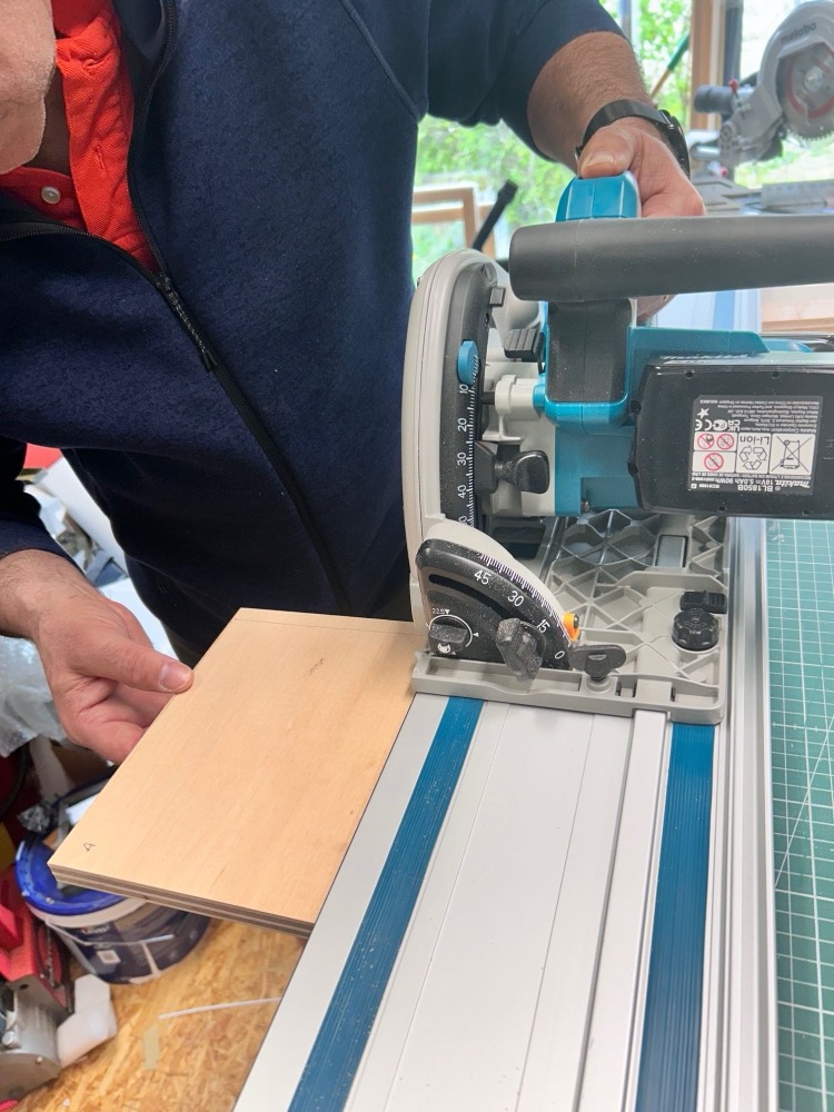 Découpe d'un panneau à la scie sur rail dans l'atelier
